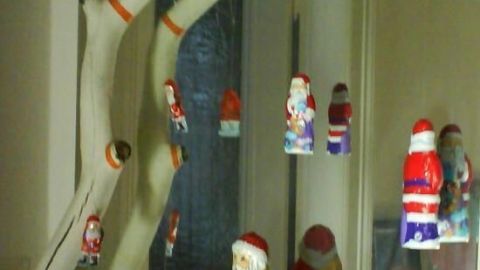Ein weißer Ast hängt dekorativ von der Decke, geschmückt mit bunten Schokoladen-Weihnachtsmännern in der Vorweihnachtszeit.