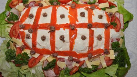 Eine große Platte mit einem dekorativen Salat, der wie ein Ei aussieht, ist mit Tomaten, Käse und Kräutern garniert.