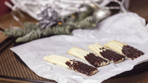 Auf Butterbrotpapier liegen mehrere Schokoladenüberzogene Snacks, umgeben von festlicher Dekoration.