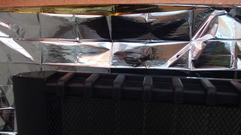 Ein Heizkörper ist mit einer Rettungsdecke versehen, die Wärme reflektiert, um Heizkosten zu sparen.