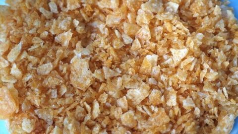 Zerkleinerte Corn Flakes liegen auf einem Teller, bereit zum Panieren von Schnitzeln in einer Küche.