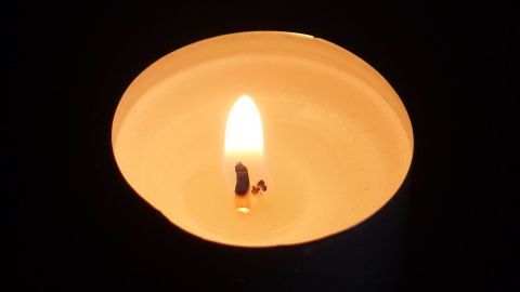 Eine brennende Kerze leuchtet hell, während der abgebrochene Docht mit einem Holz-Zahnstocher stabilisiert wird.