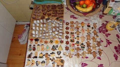 Eine Vielzahl von dekorierten Keksen liegt auf einem Tisch, umgeben von Obst und anderen Küchenutensilien.