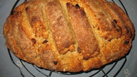 Leckeres Mandel-Rosinen-Brot liegt auf einem Drahtgitter, frisch gebacken und goldenbraun, mit knuspriger Kruste.