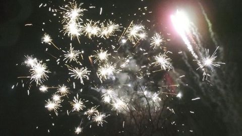 Funkelnde Silvesterfeuerwerke erhellen den Nachthimmel, während Kinder ohne Alkohol anstoßen und feiern.