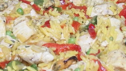 Ein buntes Gericht mit Hähnchen, Reis und Gemüse wird zubereitet, ideal für eine cholesterinbewusste Ernährung.