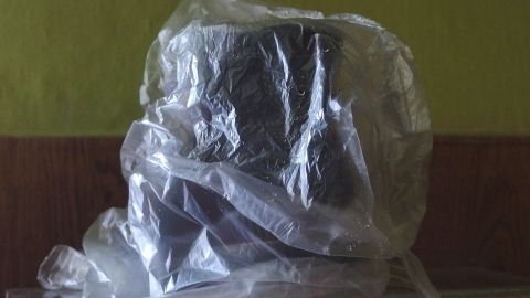Ein Paar Schuhe ist in einem durchsichtigen Plastiktütchen verpackt, um sie vor Staub zu schützen, auf einer Holzoberfläche.
