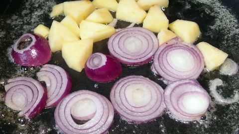 Rote Zwiebeln und gewürfelte Äpfel braten in einer Pfanne, um eine köstliche Apfel-Zwiebel-Verlockung zu kreieren.