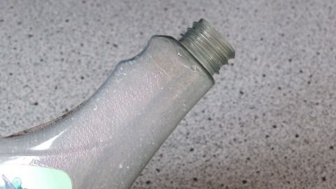 Günstiges Putzmittel mit Wasser und Spülmittel selbst gemacht. Eine Flasche mit einem leicht geöffneten Deckel steht auf einer strukturierten Oberfläche, bereit für selbstgemachte Putzmittel.
