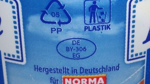 Ein Plastikbehälter zeigt Recyclingzeichen und Informationen zur Herstellung für die Marke Norma.