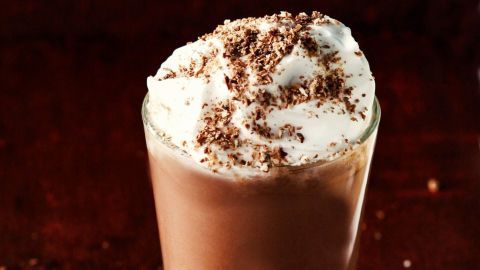 Ein Glas Eierlikörcappuccino zeigt die mehrschichtige Getränkekreation mit brauner Schaumhaube und Schokoladenspänen.
