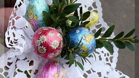 Ein buntes Biedermeiersträußchen mit Ostereiern und Buchsbaum ist auf einem hübschen, weißen Spitzenuntersetzer arrangiert.