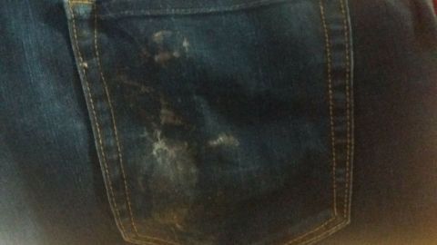 Wenn man Kaugummi auf der Hose kleben hat, einfach das komplette Kleidungsstück in die Gerfriertruhe geben, dann lässt sich der gefrorene Kaugummi ganz einfach entfernen. Eine Jeans mit Kaugummi-Flecken liegt auf einem hellen Untergrund, offensichtlich verschmutzt und unordentlich.