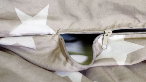 Kaputter Reißverschluss an einem Bettbezug mit Sternenmuster ist geöffnet; zeigt Verschleiß im Wohnumfeld.