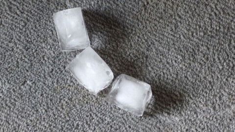 Eiswürfel liegen auf einem Teppich, wo sie schmelzen und Druckstellen im Teppich verhindern sollen.