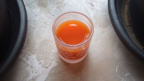 Ein Glas Karottensaft steht auf einer glatten Oberfläche zwischen zwei Töpfen, bereit zur Bekämpfung von Trauermücken.