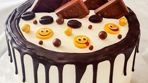 Eine schokoladige Ruck-Zuck-Torte mit Schokoladenstücken und fröhlichen Dekoren in strahlendem Licht auf einem Tischtuch.