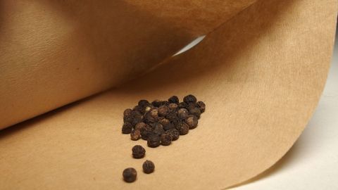 Schwarze Pfefferkörner liegen auf einem Kaffeefilter, während sie zum Füllen von Gewürzmühlen vorbereitet werden.