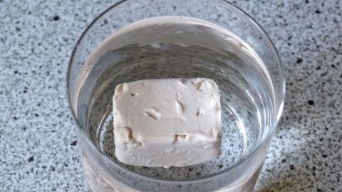 Ein Würfel Hefe liegt in einem Glas Wasser, um die Frische der Hefe zur Überprüfung zu testen.