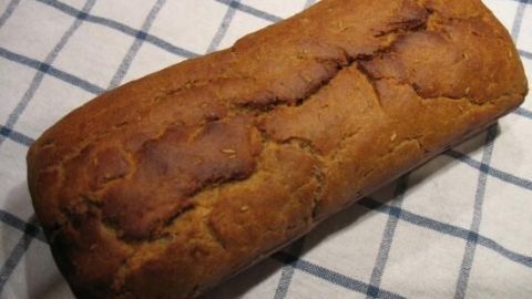 Ein rustikales Rosmarin-Brot liegt auf einem karierten Küchentuch und zeigt eine goldbraune, knusprige Oberfläche.