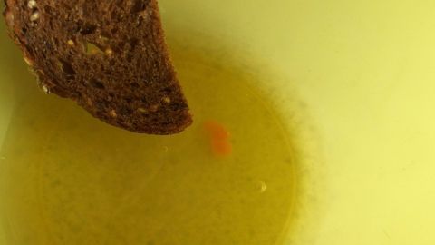 Ein Stück Brot wird in eine Schüssel mit Eiweiß und einem Eigelb eingetaucht, das in der Mitte sichtbar ist.