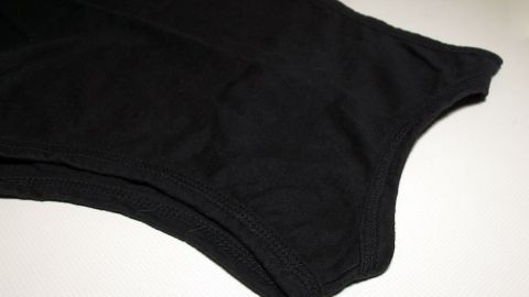 Ein schwarzes T-Shirt liegt flach auf einer Oberfläche und kann im Winter umgekehrt getragen werden, um die Brust zu schützen.