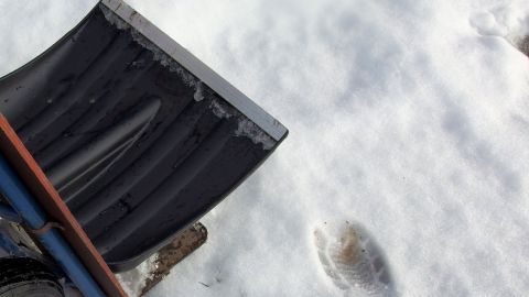 Eine Schneeschaufel mit Rädern liegt auf dem Schnee, bereit zum einfachen Schneeräumen mit der Sackkarre.