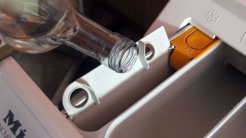 Eine Flasche wird in das Waschmittelfach einer Miele-Waschmaschine eingeführt, um sie richtig zu reinigen.