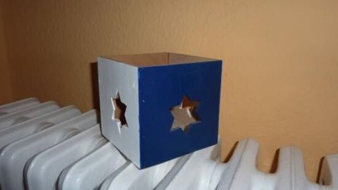 Ein Teelichthalter steht auf einem Heizkörper, während er glitzern soll und durch die Sterne Licht ausstrahlt.
