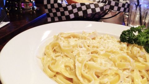Eine schüssel Linguine mit Gorgonzola-Sahnesauce steht auf einem Tisch, umgeben von einem Restaurant-Ambiente.