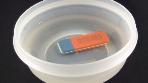 Ein Radiergummi schwimmt in einer Schüssel mit Wasser, seine Reinigung wird durch das Nassen ermöglicht.
