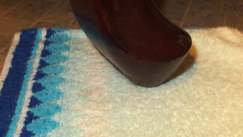 Ein Möbelstück steht auf einem Waschlappen, um Kratzer auf dem Boden zu vermeiden. Die Szene zeigt eine einfache Haushaltslösung.