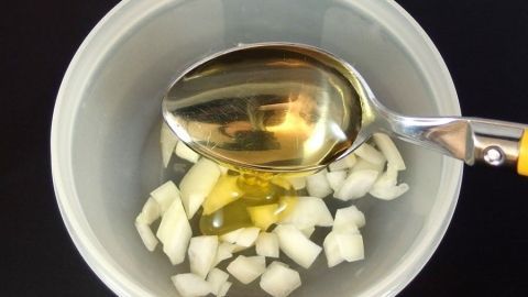 Zwiebelstückchen liegen in einer Schüssel und werden mit Honig vermischt, um einen Hustenstiller herzustellen.