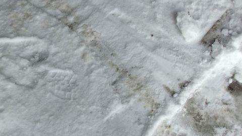 Schnee bedeckt eine Fläche, während Abdrücke darauf sichtbar sind, was eine Reinigung mit Schnee andeutet.