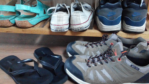 Schuhe stehen ordentlich im Flur, während bequeme Flip-Flops und robuste Wanderschuhe darauf warten, getragen zu werden.
