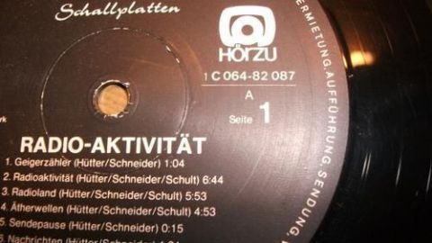 Eine schwarze Schallplatte liegt auf dem Tisch, beschriftet mit Titeln und Zeiten von Liedern einer bekannten Band.