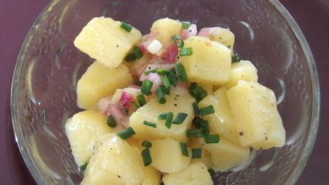 Knackiger Kartoffelsalat ohne Mayo in einer Glasschüssel, angerichtet mit frischen Kräutern und lecker gewürzt.
