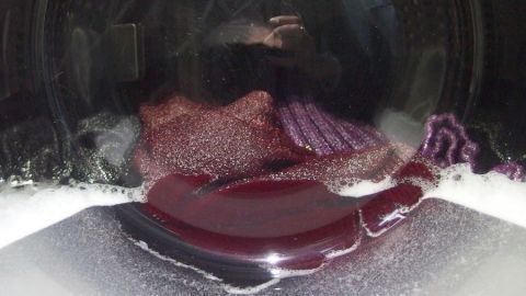 Eine Waschmaschine wäscht bunte Wäsche in Seifenlauge, um die Lebensdauer der Waschmaschine zu verlängern.