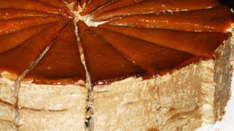Eine Joghurt-Torte mit glatter Oberseite, in gleichmäßige Stücke geschnitten, auf einem weißen Teller präsentiert.