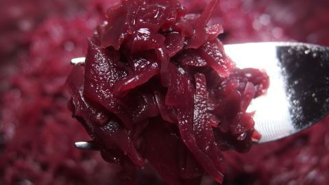 Eine Gabel hält zarten Rotkohl, der glänzend und bissfest aussieht, in einem tiefen Teller voller rotem Gemüse.