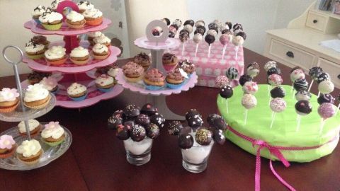 Cake Pops und Mini-Cupcakes stehen hübsch auf Ständern, umgeben von einem einladenden, hellen Raum.