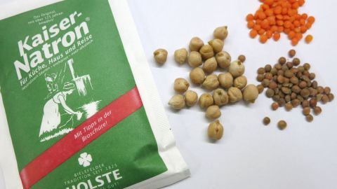 Eine Packung Kaiser-Natron liegt neben verschiedenen Hülsenfrüchten, die zum Kochen vorbereitet sind.