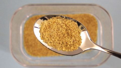 Ein Löffel mit goldbraunen Weizenkeimen schwebt über einer Schale, die diese nährstoffreiche Zutat enthält.