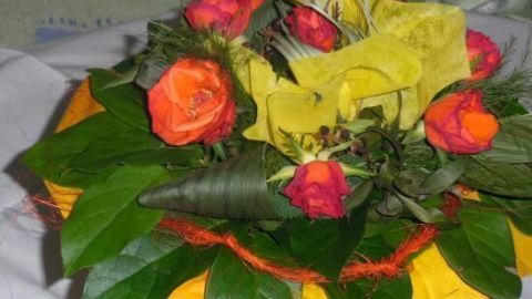 Ein bunter Blumenstrauß mit roten und gelben Rosen wird auf einem Tisch dekoriert, um ihn aufzufrischen und zu präsentieren.