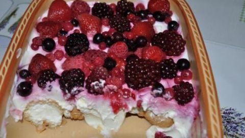 Eine Auflaufform zeigt ein angeschnittenes Dessert mit Sahne und gemischten Beeren, ideal als schneller Nachtisch.