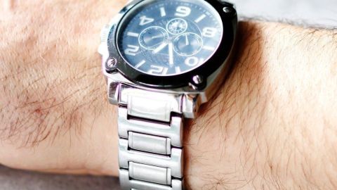 Eine Armbanduhr liegt an einem Handgelenk und zeigt die Zeit an. Die Uhr hat ein schwarzes Ziffernblatt und ein silbernes Armband.
