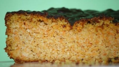 Ein saftiger Möhrenkuchen ohne Mehl, der frisch gebacken auf einem Teller präsentiert wird, mit einem grünen Hintergrund.