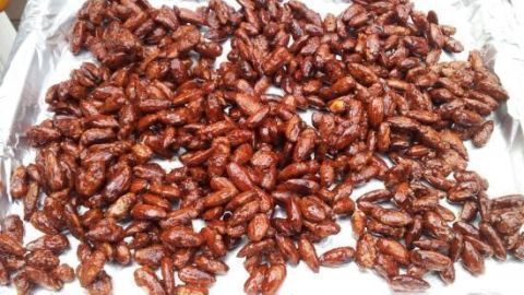 Gebrannte Mandeln liegen verteilt auf einem Blech, glänzend und knusprig, bereit zum Abkühlen und Genießen.