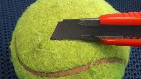 Eine grüne Tennisball-Hülle wird mit einem Cutter präzise geschnitten, um eine pfiffige Verstecklösung zu schaffen.