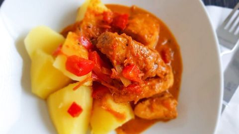 Ein köstliches Geschnetzeltes liegt in einer weißen Schüssel, umgeben von gekochten Kartoffeln und Gemüse.